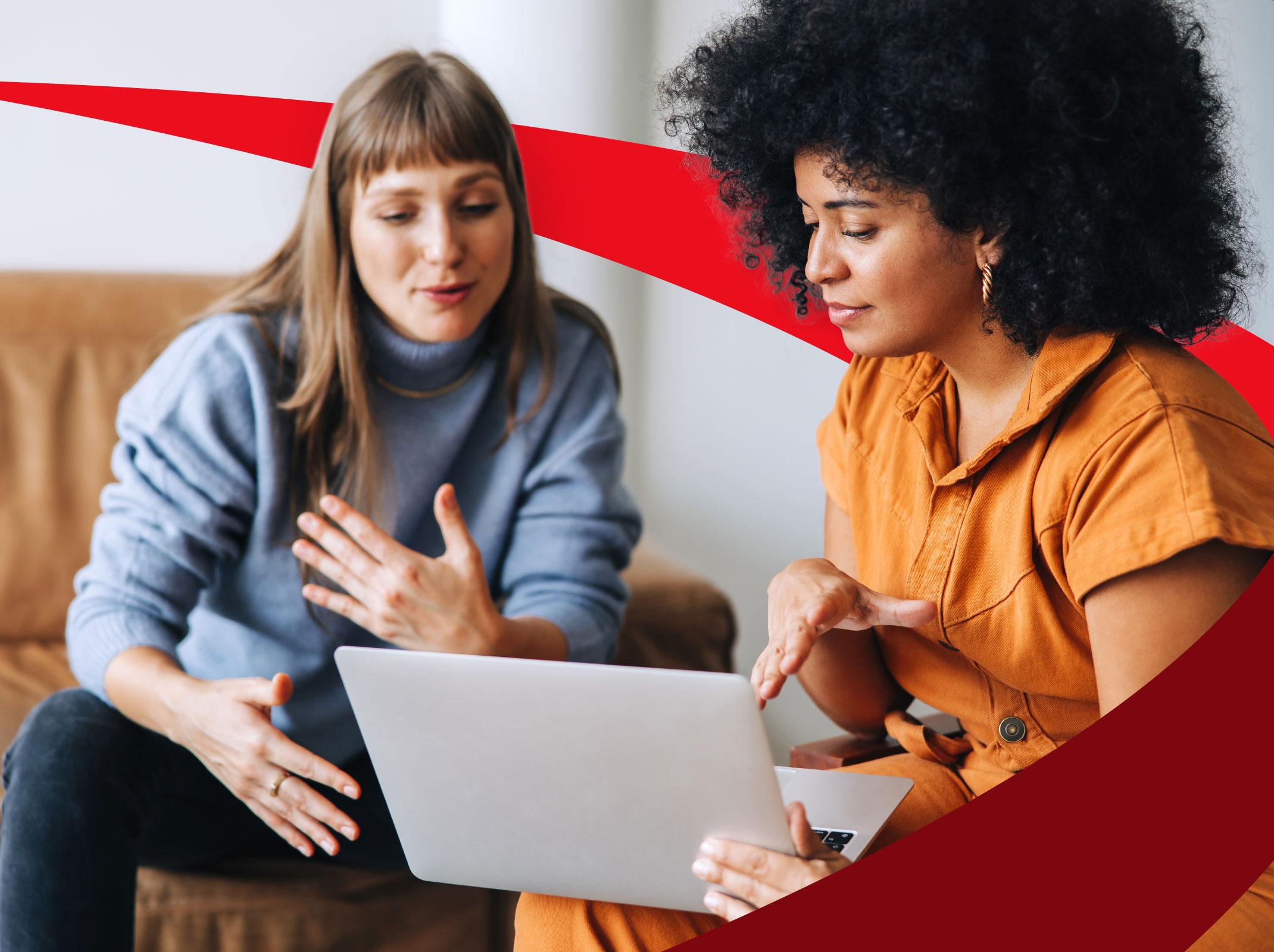 Female manager coaching a female employee over a laptop in an office setting.