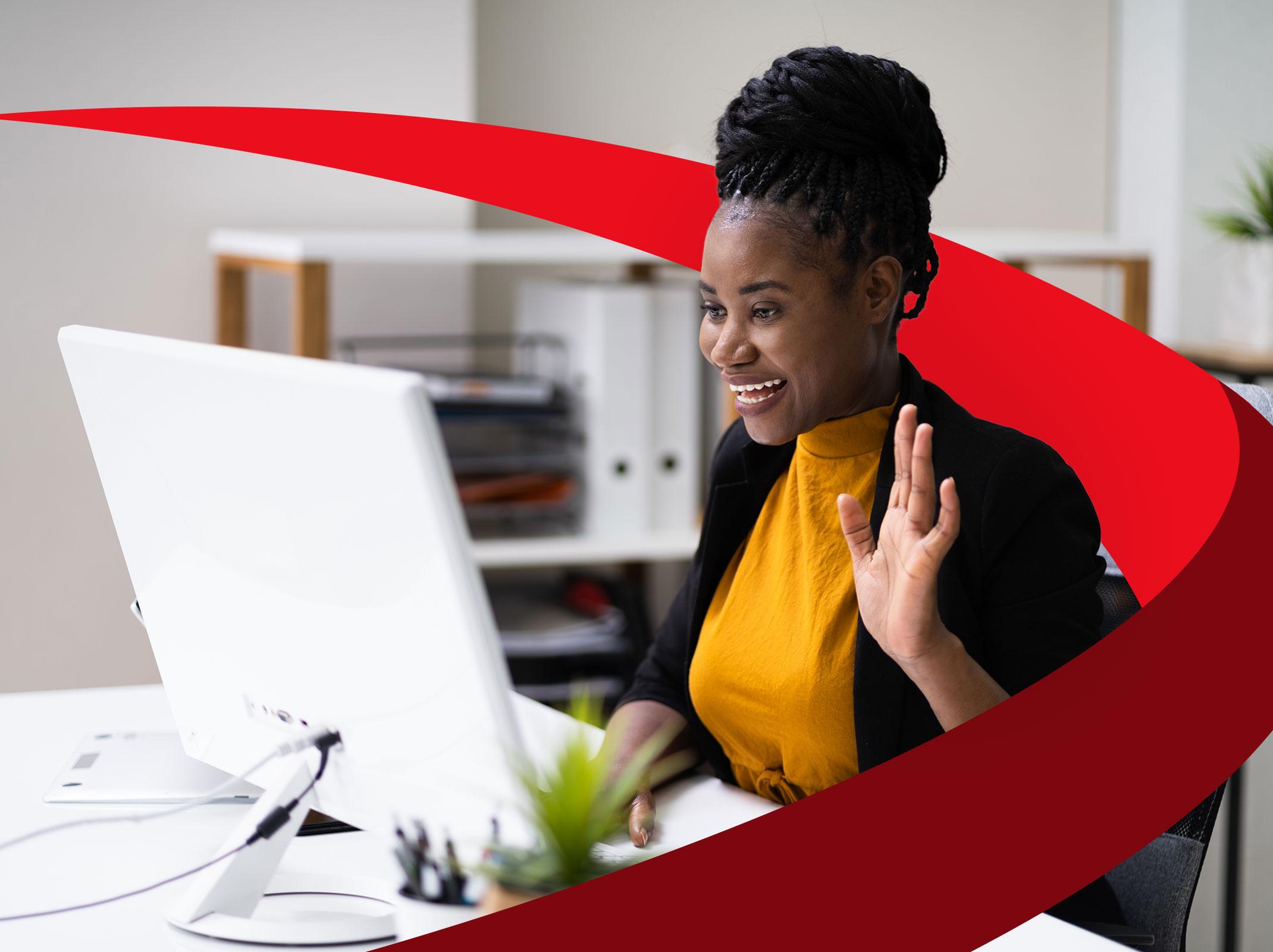 Woman waving at computer screen in a virtual onboarding meeting